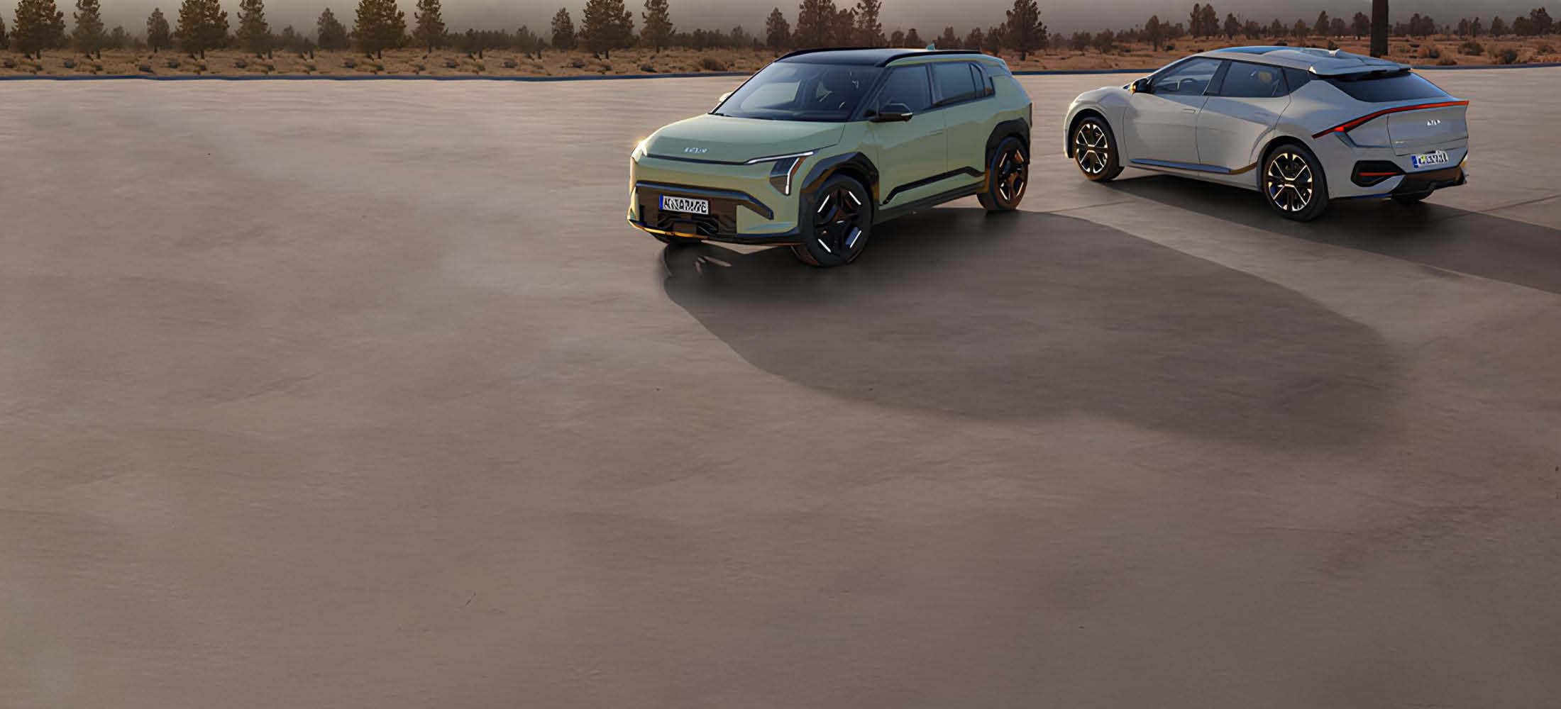 Zwei Kia-E-Modelle stehen auf einer Straße mit Landschaft im Hintergrund